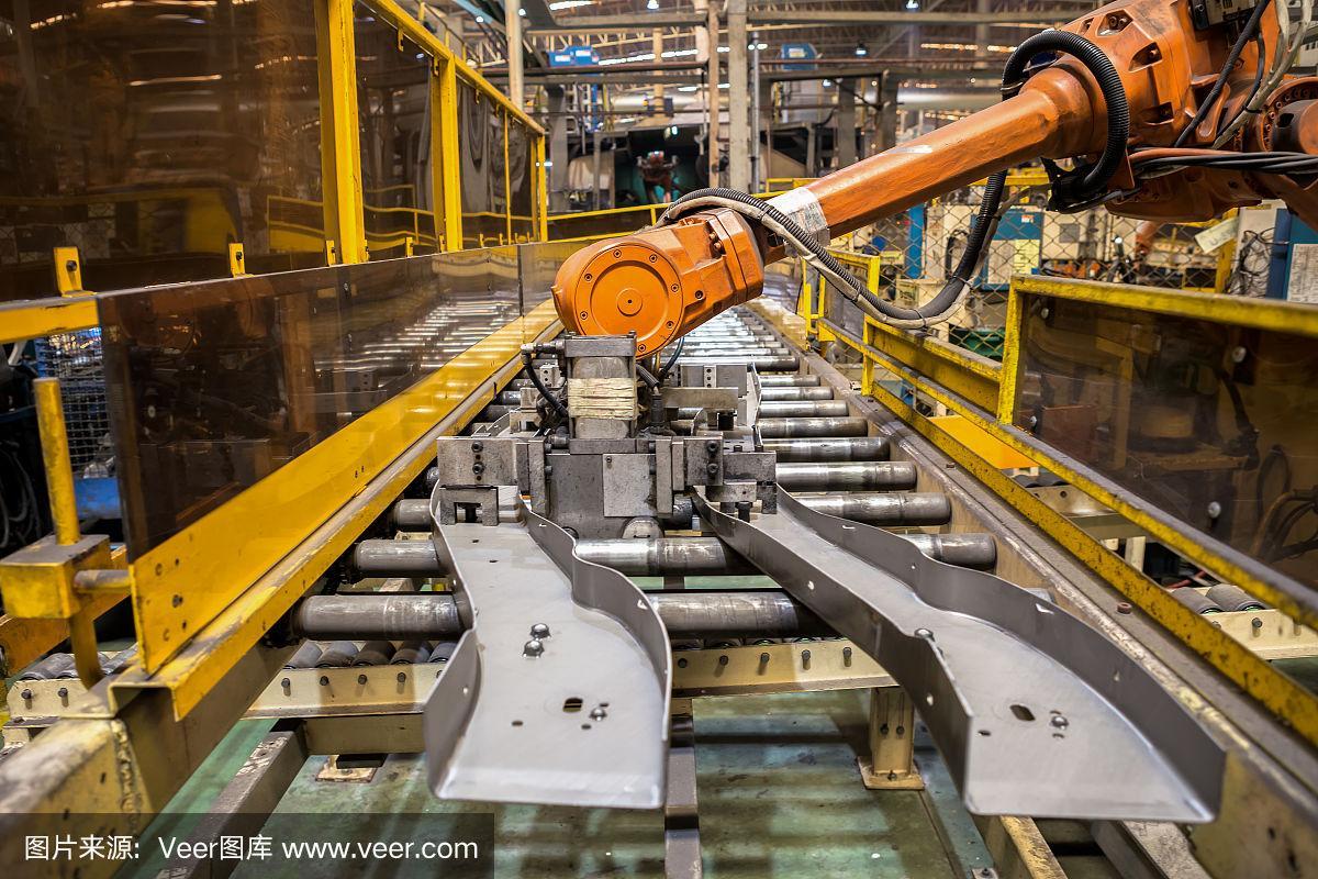 在汽车厂,机器人手臂和手柄工具保持汽车零件的现场机器